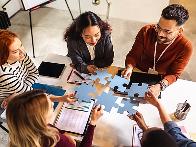 Mehrere Personen arbeiten gemeinsam an einem Puzzle bei einem kreativen Teammeeting